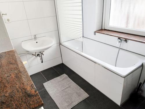 ein weißes Badezimmer mit einem Waschbecken und einer Badewanne in der Unterkunft Schöne Monteursunterkunft in Wuppertal in Wuppertal
