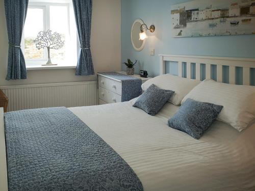 a bedroom with a bed with two pillows and a window at Seascape - St Catherines Court in Fowey