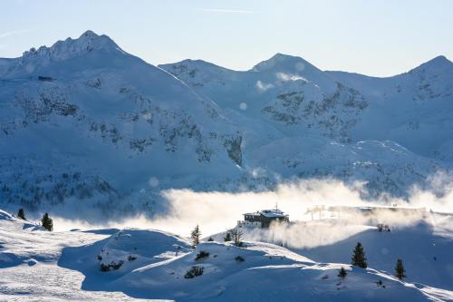 a snow covered mountain with a house in the distance at Apparthotel Samson in Obertauern