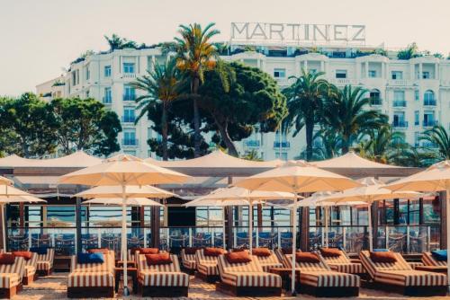 - un groupe de chaises et de parasols devant un hôtel dans l'établissement Hôtel Martinez, in The Unbound Collection by Hyatt, à Cannes