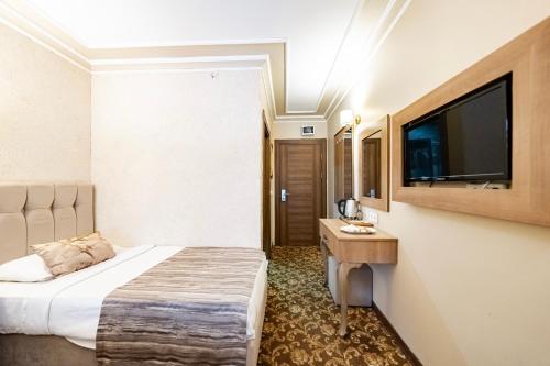 a hotel room with a bed and a flat screen tv at Hamit Hotel Kizilay in Ankara