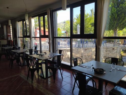 un ristorante con tavoli, sedie e ampie finestre di El ZAMACÉN a Burbáguena