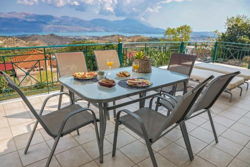 a table with food and drinks and chairs on a balcony at Villa Theano - Family House in Lixouri, Kefalonia in Lixouri