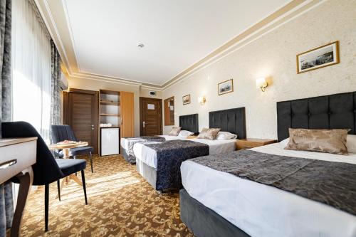 a hotel room with three beds and a desk at Hamit Hotel Kizilay in Ankara