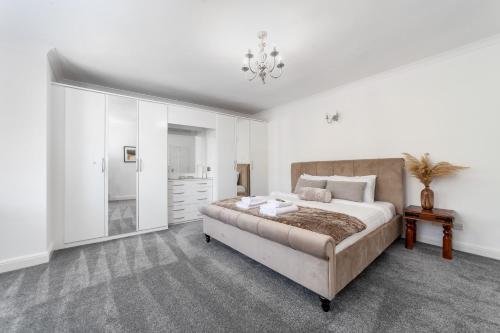 Habitación blanca con cama grande y lámpara de araña. en Fantastic 2BR flat wpriv Gdn, Crouch End, en Londres