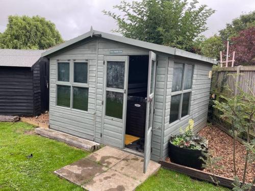 a grey shed with a door in a yard at The Firkin Lodge in Whaplode