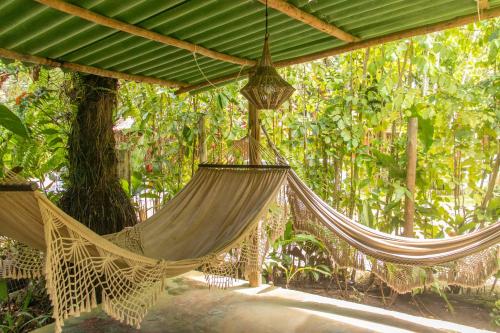 two hammocks hanging from a canopy in front of trees at Villa Residencial Encantos Da Mata in Itacaré