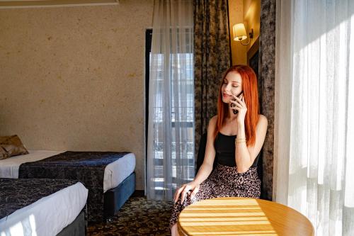 a woman sitting in a hotel room talking on a cell phone at Hamit Hotel Kizilay in Ankara