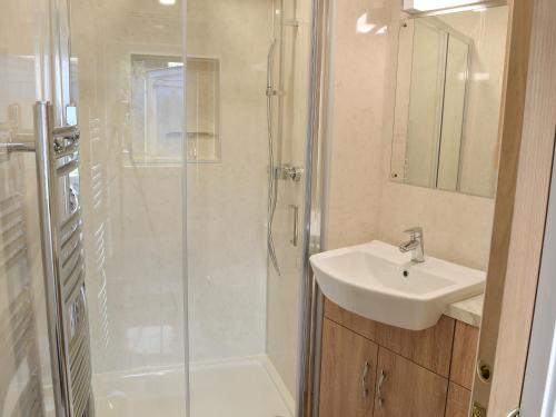 uma casa de banho com um chuveiro, um lavatório e um chuveiro em Knights Den em Port Isaac