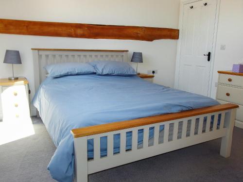 a bedroom with a large bed with a wooden headboard at Red Barn Cottage in Kettleburgh