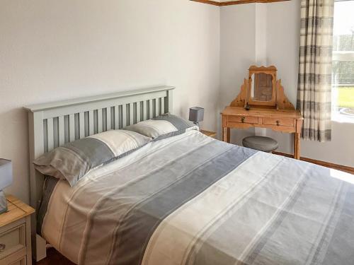 a bedroom with a bed and a table and a mirror at Penfound Country Cottage in Poundstock