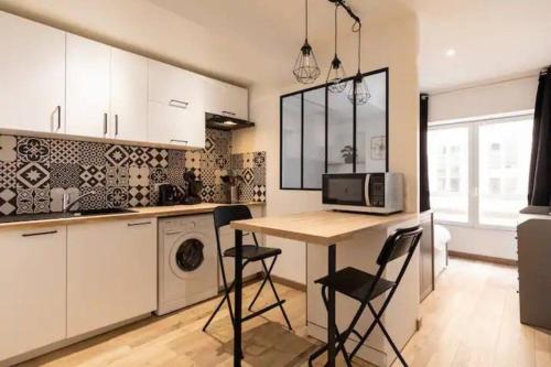 une cuisine avec une table avec des chaises et un micro-ondes dans l'établissement Le Flesselles - Hyper centre - Calme et cosy, à Lyon