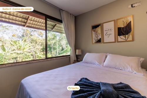 ein Schlafzimmer mit einem Bett und einem großen Fenster in der Unterkunft Triplex de luxo na Serra de Guaramiranga por Tactu in Guaramiranga