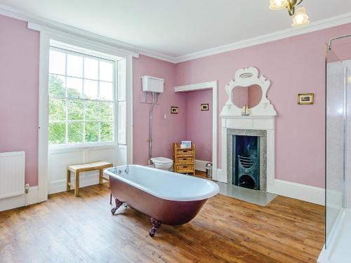 a bathroom with a tub and a fireplace at Lode Hall in Upwell