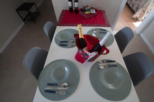 a white table with two plates and a bottle of wine at 4 Apartamentos amplos e novos, 86m e 45m, excelente localização, garagem, 350Mb de internet in Bento Gonçalves