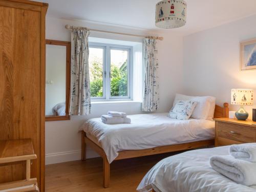 a bedroom with two beds and a window at Spring Barn in Hope Cove
