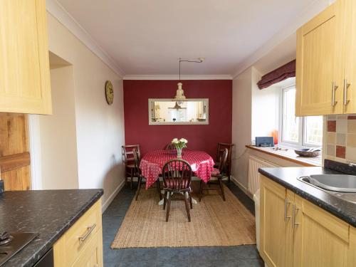 uma cozinha com uma mesa com uma toalha de mesa vermelha em Little Roost em Mathry