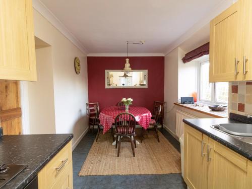 a kitchen with a table with a red table cloth at Little Roost in Mathry