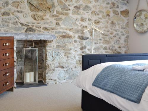 1 dormitorio con pared de piedra, cama y chimenea en Tan Y Fford en Bangor