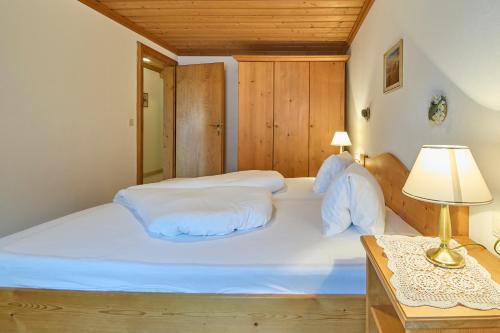 a bedroom with a large white bed and a table at Appartements Bernhofer in Saalbach Hinterglemm