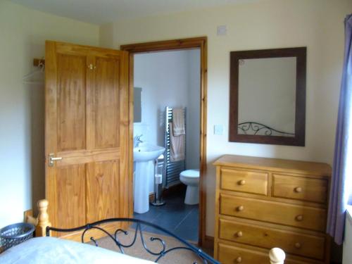 1 dormitorio con tocador, lavabo y espejo en Tan Rallt Barn, en Tregarth