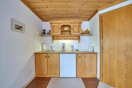 a kitchen with wooden cabinets and a white refrigerator at Appartements Bernhofer in Saalbach Hinterglemm