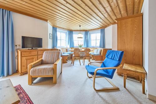 a living room with blue chairs and a television at Appartements Bernhofer in Saalbach Hinterglemm