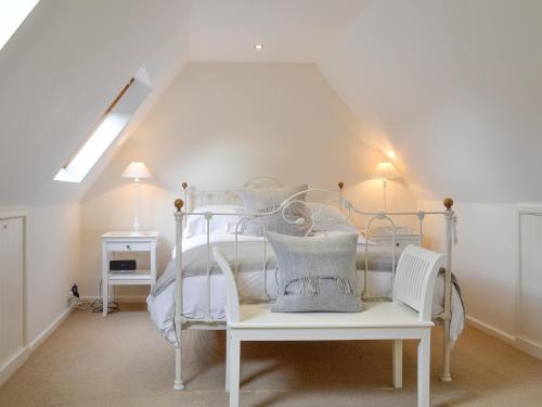 a bedroom with a white bed with a white chair at Brookside Cottage in Burley