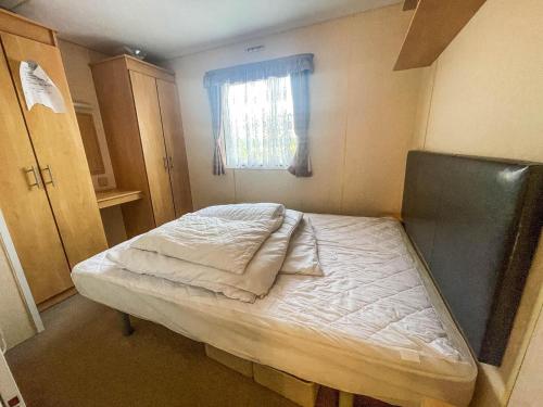 a small bed in a room with a window at 8 Berth Caravan At California Cliffs By Scratby Beach In Norfolk Ref 50001d in Great Yarmouth