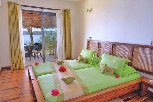 una camera da letto con un grande letto verde con sopra dei fiori di ANJARA LODGE Villa de 3 chambres a Nosy Be