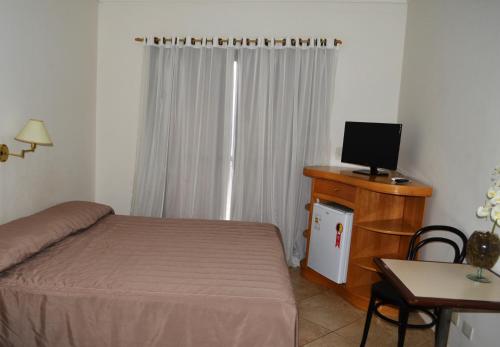 a bedroom with a bed and a desk with a computer at Hotel São Luiz in Águas de Lindoia