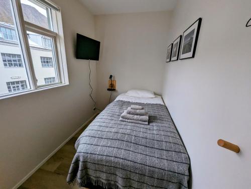 a bedroom with a bed with a blanket and a window at The Ísafjörður Inn in Ísafjörður