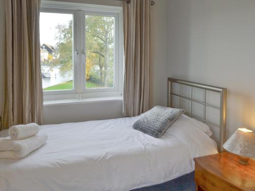 a bedroom with a white bed with a window at Davids Island in Wroxham