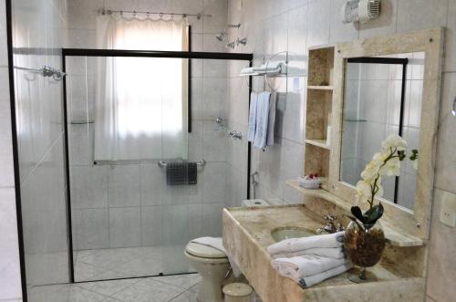 a bathroom with a shower and a toilet and a sink at Hotel São Luiz in Águas de Lindoia