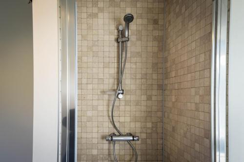 een douche met een douchekop in de badkamer bij Rooms De Voerman in Ieper