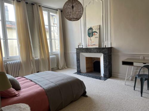 a bedroom with a fireplace and a bed and a table at Hôtel particulier Champenois in Chalons en Champagne