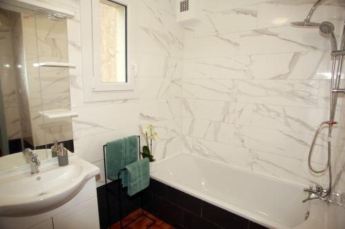 uma casa de banho com uma banheira branca e um lavatório. em La maison verd'O Sisteron em Sisteron
