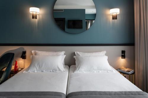 a hotel room with two beds and a mirror at Lenox Montparnasse in Paris