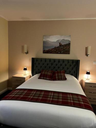 a bedroom with a large bed with two night stands and two lamps at Britannia Inn Glasgow in Glasgow