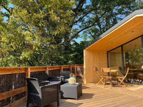 a wooden deck with chairs and tables on a house at Domaine des Constellations - Gîtes & Bains Nordiques in Orbey