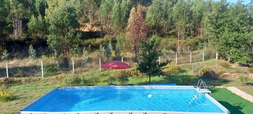 uma piscina com um guarda-chuva vermelho e um guarda-chuva em Quinta D' LuzArcoIris em Arganil