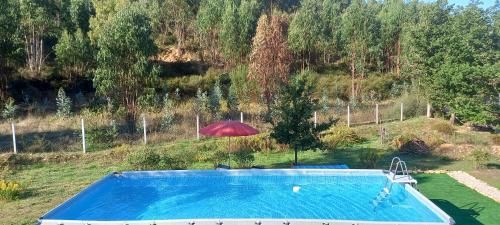 a swimming pool with a red umbrella and an umbrella at Quinta D' LuzArcoIris in Arganil
