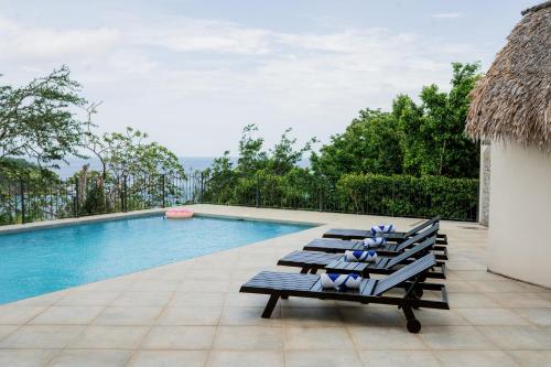 南聖胡安的住宿－Seaside Serenity at Casa Cala Azul home，一组躺椅,坐在游泳池旁