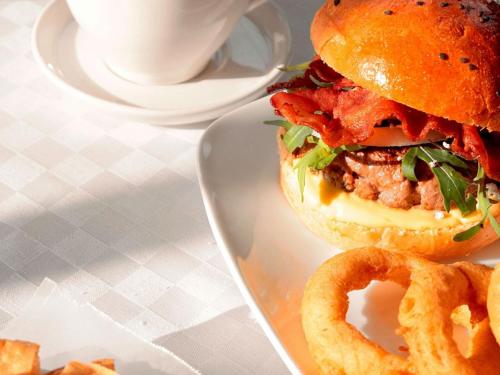 a hamburger and onion rings on a plate with a cup of coffee at Piccadilly Inn Airport in Fresno