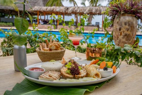 ein Teller mit Essen auf einem Tisch neben einem Pool in der Unterkunft Michamvi Sunset Bay in Michamvi