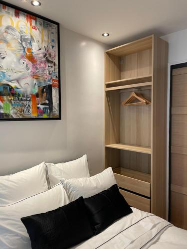 Un dormitorio con una cama blanca y un cuadro en la pared. en Cosy Studio paris 16 Victor Hugo, en París