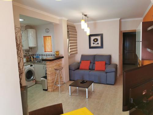 a living room with a blue couch and a kitchen at Benicarlo Puerto in Benicarló