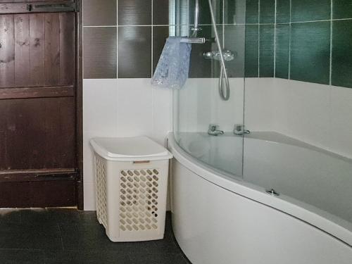 a bathroom with a bath tub and a trash can at Haycraft Cottage in Langton Matravers