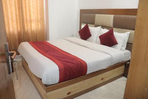 Schlafzimmer mit einem Bett mit roten und weißen Kissen in der Unterkunft Hotel Tourist Home By palak Hospitality in Masuri