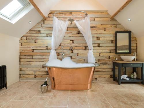 a large tub in a bathroom with a wooden wall at The Coach House in Ridingmill